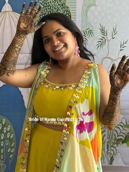 A glowing bride at her mehendi ceremony. Her joyful expression and colorful outfit are the perfect backdrop for the intricate henna art on her arms.