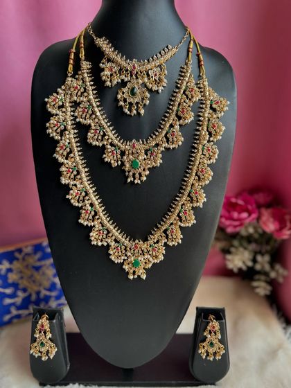 A layered bridal necklace set featuring green and red stones with pearl detailing. This three-layer design provides a complete and grand look for a bride.