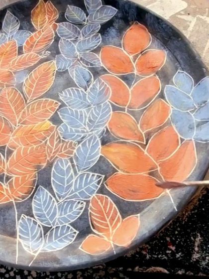 After the base colors are applied, I begin the sgraffito process. Here, I am carefully carving away the top layer of color to reveal the white clay underneath, creating the outlines of the leaves.