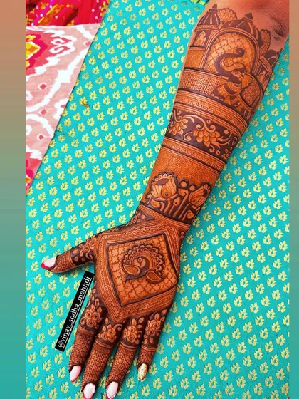 A full-arm back-of-hand design showcasing a variety of motifs, including peacocks, elephants, and architectural domes.
