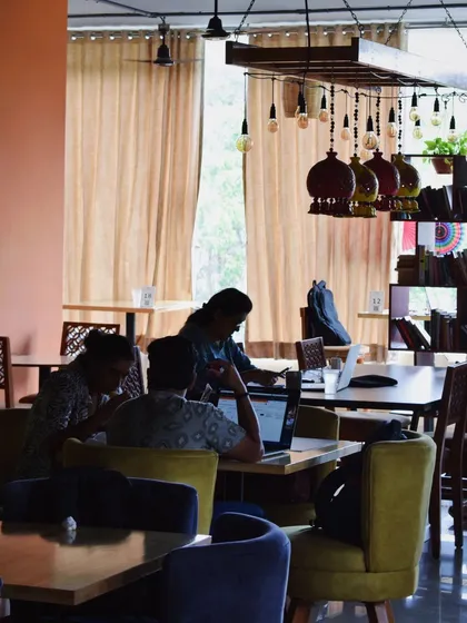 Here is a glimpse of a typical day, with people dedicated to their work in a comfortable and collaborative setting. The warm lighting and shared tables encourage focus and community.