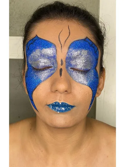 With eyes closed, you can see the full effect of the glitter butterfly wings. This demonstrates the complete artistry involved in creating symmetrical and impactful editorial makeup.