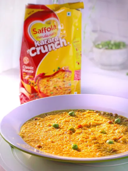 A close-up on the bowl of Saffola Masala Oats, focusing on the texture of the food and the fresh green peas.