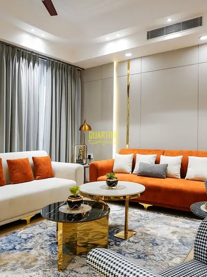 This view highlights the wall treatment in the Apex D'Rio living room, where simple grey panels are elevated with vertical gold strips and integrated lighting, adding a touch of glamour and defining the seating area.