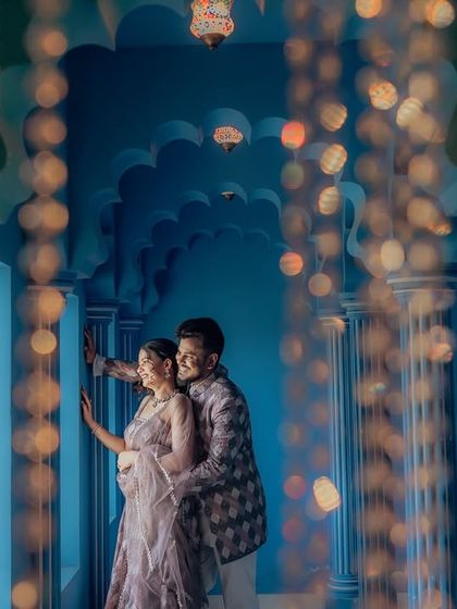 A creative shot using bokeh from fairy lights to frame the couple in a royal blue corridor. This technique adds a dreamy, magical quality to the portrait, blending architectural beauty with romantic lighting.