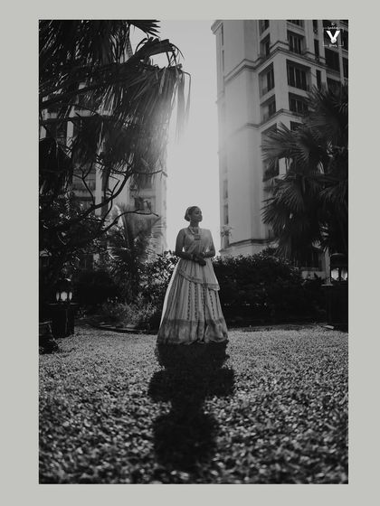 A stunning black and white portrait of the bride in a garden. The strong backlight creates a beautiful silhouette effect, highlighting her form against the bright sun.
