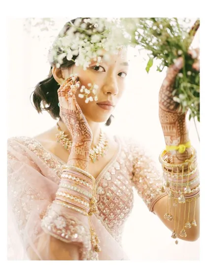 An artistic bridal portrait with a fine art feel. The bride's pose, combined with the delicate flowers, creates a beautiful and ethereal image that feels both candid and composed.