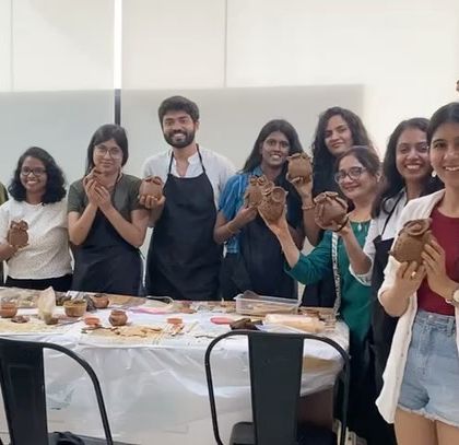 A group of participants from a pottery workshop, all happy with their handmade creations.
