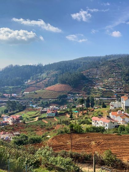 A view of the terraced farms and houses that dot the hillsides of Ooty. The landscape is a beautiful patchwork of nature and human settlement.