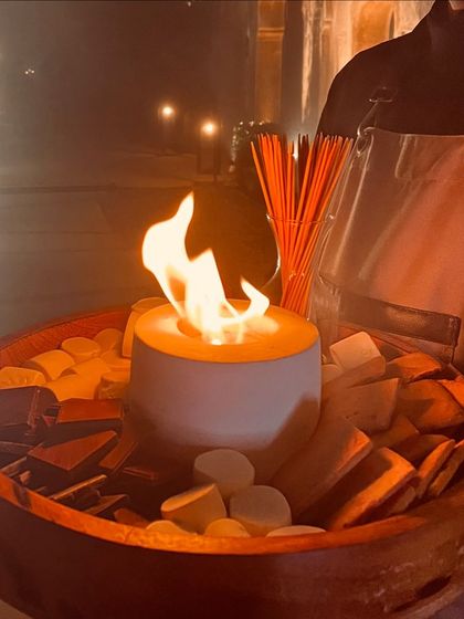 An interactive S'mores station brings a touch of playful nostalgia to an elegant evening. A server presents the portable fire pit, allowing guests to toast their own marshmallows under the stars.