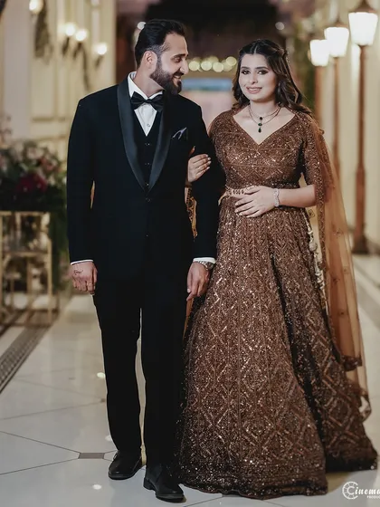 The couple walks arm-in-arm through a beautifully lit corridor. This shot captures the style and grace of their engagement celebration.