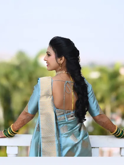 The back view of this bride's first engagement look, featuring a beautiful long braid and a stylish low-back blouse.