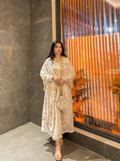 A full-length portrait in the white and gold ethnic suit, showing how it looks from head to toe against a modern, contrasting background.
