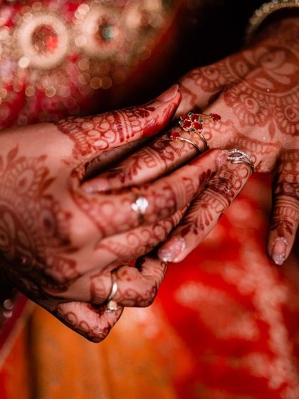 A close-up of the bride's hands, showcasing the intricate henna design and her beautiful wedding rings.