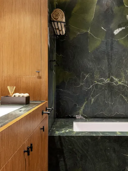 The bathroom adjoining the photographer's bedroom features a dramatic avocado marble. The deep green stone, with its natural veining, is paired with fluted wood to continue the home's material theme.