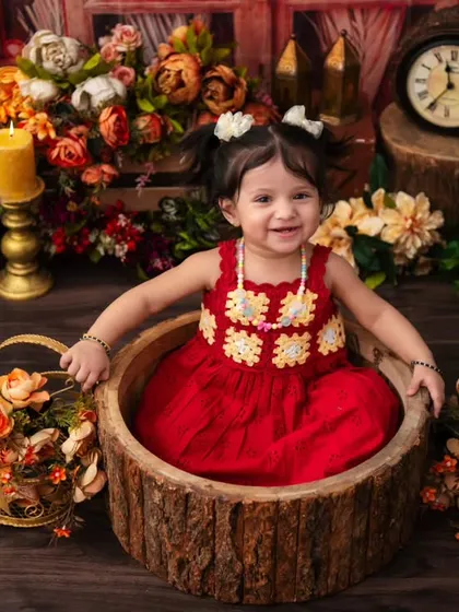 A charming first birthday photo in a rustic log tub. The combination of natural wood, warm candlelight, and floral arrangements creates a cozy and magical scene.