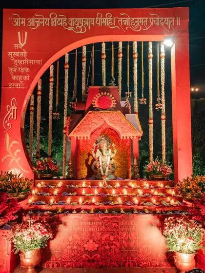 A shrine for Lord Hanuman set up for the Sunderkand path. The deity is placed within a red arch adorned with marigold garlands and surrounded by glowing diyas.