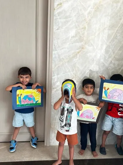 A group of proud young students showing off their finished elephant drawings. Group classes at home are a great way for friends to learn and create together.