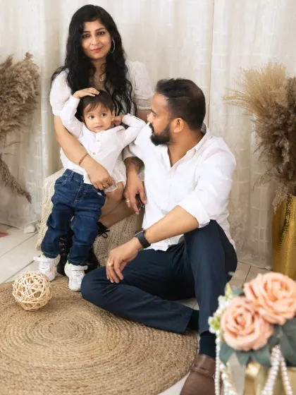 A relaxed family portrait in the studio, with parents and their child sitting together in a casual and loving pose.