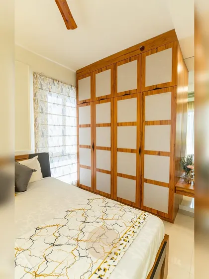 A beautiful example of a custom hinged wardrobe with fabric-paneled shutters. The combination of wood and textured fabric adds warmth and softness to the bedroom, moving beyond standard laminate finishes.