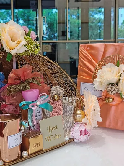 A wider view of the wedding hamper, showing the golden basket and the beautifully wrapped gift box, both decorated in a matching peach and cream floral theme.