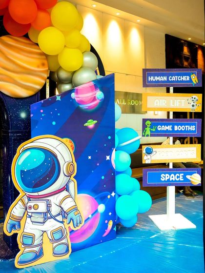 A space-themed signpost directing guests to activities like "Human Catcher," "Air Lift," and "Game Booths."
