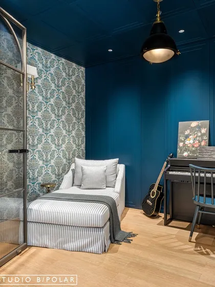 A view of the music room, showing the striped daybed, patterned wallpaper, and the glass partition that connects it to the rest of the home. It's a perfect example of a room within a room.