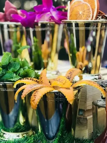 A detailed look at the fresh botanicals available at the gin bar. Mint, edible flowers, and citrus peels are beautifully displayed in metallic cups, offering a feast for the senses and endless cocktail possibilities.