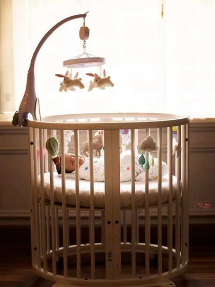 A wider shot showing the baby's crib against the backdrop of a window. This image captures the peaceful atmosphere of the nursery and the start of a new life.