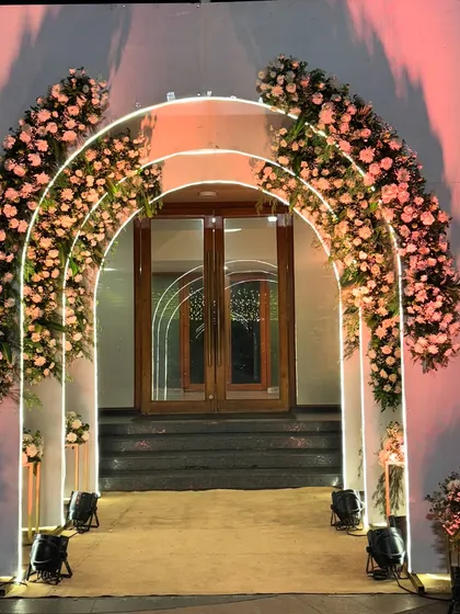 The glowing arch entrance seen from a different angle, highlighting the soft pink light and the lush flowers climbing the sides.