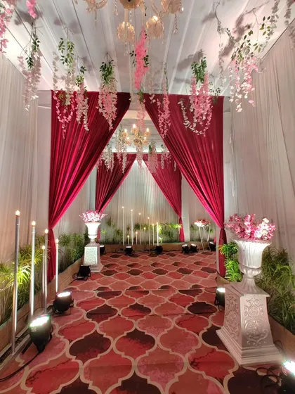 This view from the end of the walkway shows the full effect of the draped entrance. The path is lined with floral urns and warm lights, creating a beautiful and welcoming passage for guests.