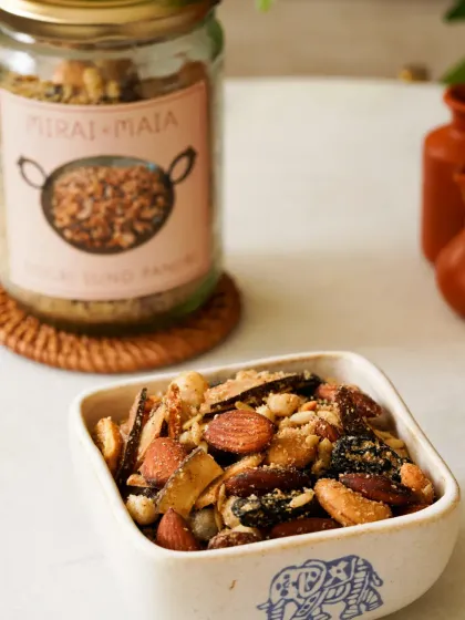 A close-up of a traditional panjiri mix, with the product jar in the background. The focus is on the texture and ingredients of the snack.