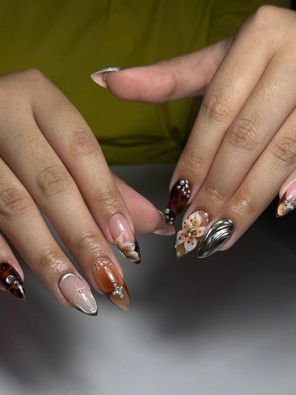 A complex and artistic set featuring a mix of textures and embellishments, including 3D chrome, floral painting, and rhinestones.