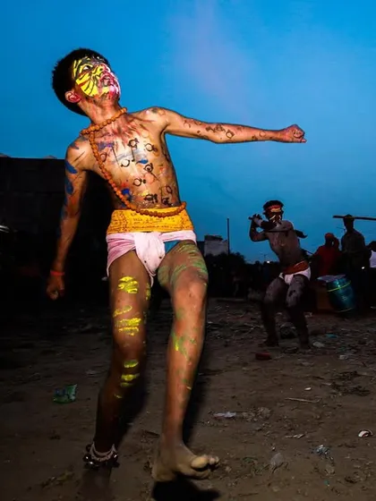 A young man dances with abandon during the Gajan festival, his body painted and his expression one of pure ecstasy.