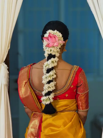 A perfectly framed shot of Dr. Sushmita's floral braid against a simple backdrop. This photo emphasizes the artistry of the traditional hairstyle, a key element of the South Indian bridal look.