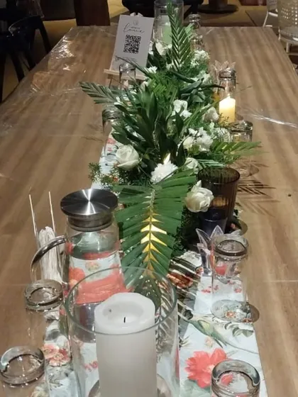 The tablescape for this minimal wedding features a simple runner of fresh greenery and white flowers, accented with candles. This creates an elegant and uncluttered dining experience for guests.
