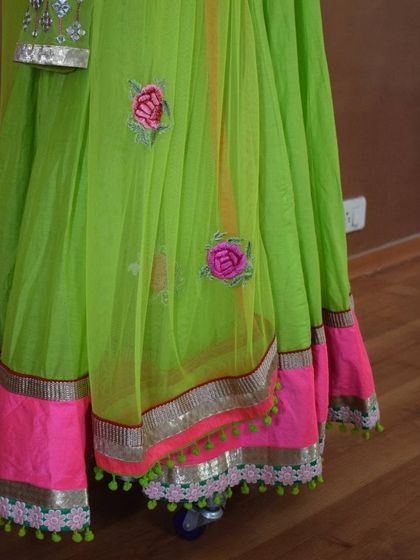 A detail shot of the lime green Anarkali's net dupatta, showing the scattered floral embroidery and the playful pom-pom border. It’s these little touches that complete the look.