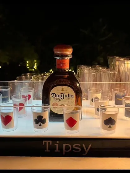 A custom shot tray designed for a casino-themed party. The shot glasses are decorated with card suit symbols, and the tray is lit from below for a dramatic effect.