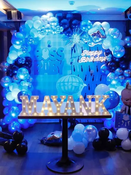A cool and stylish Boss Baby themed birthday party. The deep blue lighting, custom balloon arches in shades of blue, black, and white, and marquee letters create a sophisticated and fun atmosphere for the little boss.