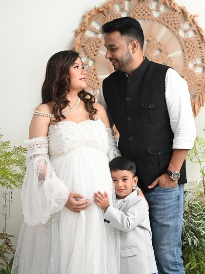 A sweet, candid moment between mother, father, and son during their maternity shoot. The little boy looks up at his parents, sharing in their joy and anticipation.