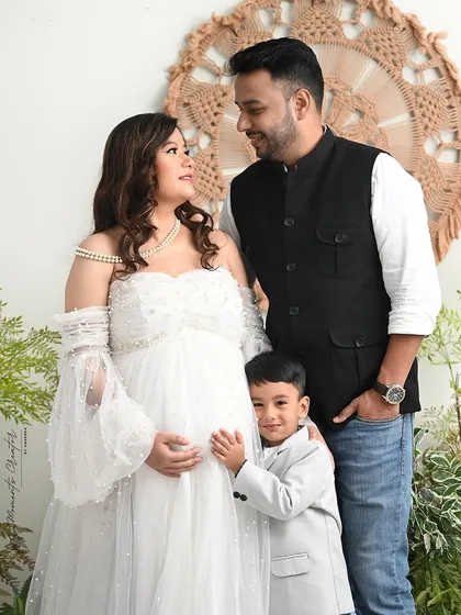 A beautiful family moment. The older son peeks out from behind his parents, adding a touch of playfulness to this lovely family portrait.