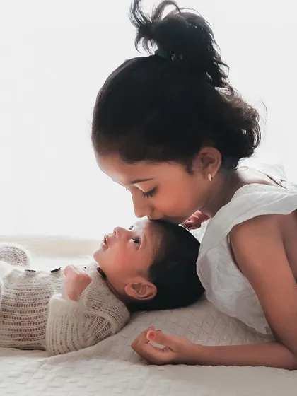 A quiet kiss on the forehead from a loving big sister. These are the tender moments that truly define the sibling bond.
