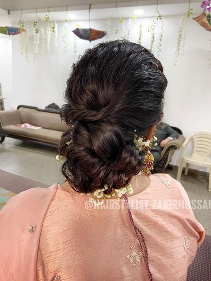 A soft, romantic low bun with loose tendrils framing the face. This textured updo is decorated with baby's breath for a delicate and feminine touch, perfect for an engagement or reception.