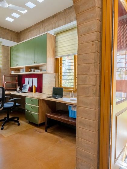 The study room is designed for focus and comfort, with ample daylight from windows and glass block skylights. The walls are left unplastered, showcasing the natural texture of the earth blocks.