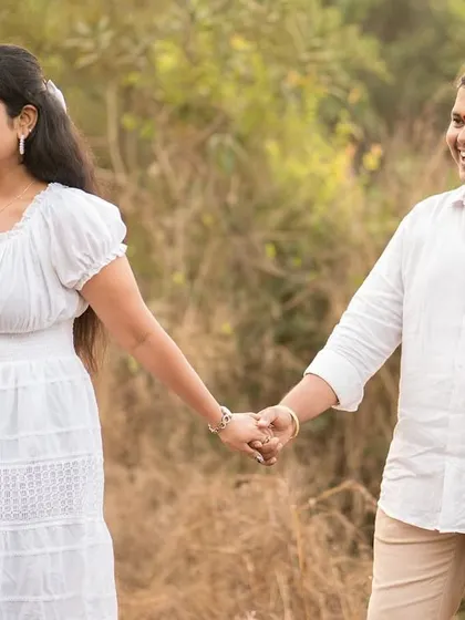 A candid shot of a couple holding hands and walking through a sunlit field. Their natural smiles and relaxed posture reflect the peaceful and easygoing nature of their relationship.