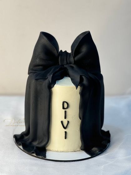 A chic and modern cake with a bold, black fondant bow. The minimalist design and personalized name make it a sophisticated choice for a birthday.
