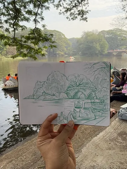 There is a special connection formed when you draw a place while you are in it. I held up my finished sketchbook to show my pen drawing against the real boating lake at Sanjay Gandhi National Park. My goal is to capture the essence of the scene, not just a perfect copy.