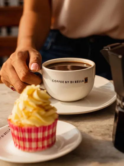 A slightly different angle of the coffee and cupcake pairing. This composition feels natural and relaxed, like a snapshot of a pleasant afternoon break.