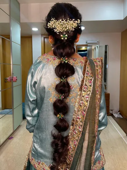 A messy balloon braid decorated with colorful jewels and baby's breath. This is a creative and festive style, ideal for a mehendi or sangeet.