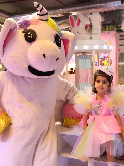 A birthday girl in her beautiful dress poses with our magical unicorn mascot.